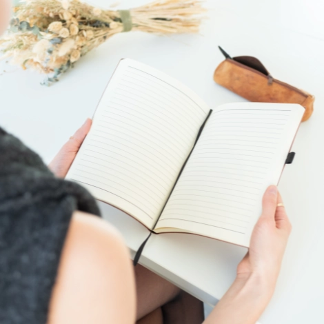 Carnet ligné ouvert par une personne avec une trousse et un bouquet